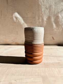 Textured Tumbler: close front view of a cup with speckled light glaze and a horizontally ridged raw clay base.