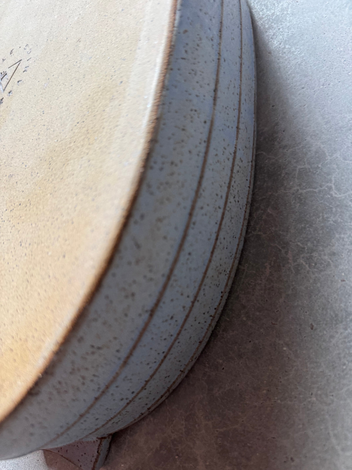 Speckle Cenote Hot Dish, close cropped view of unglazed raw clay underside edge and grooved exterior wall.
