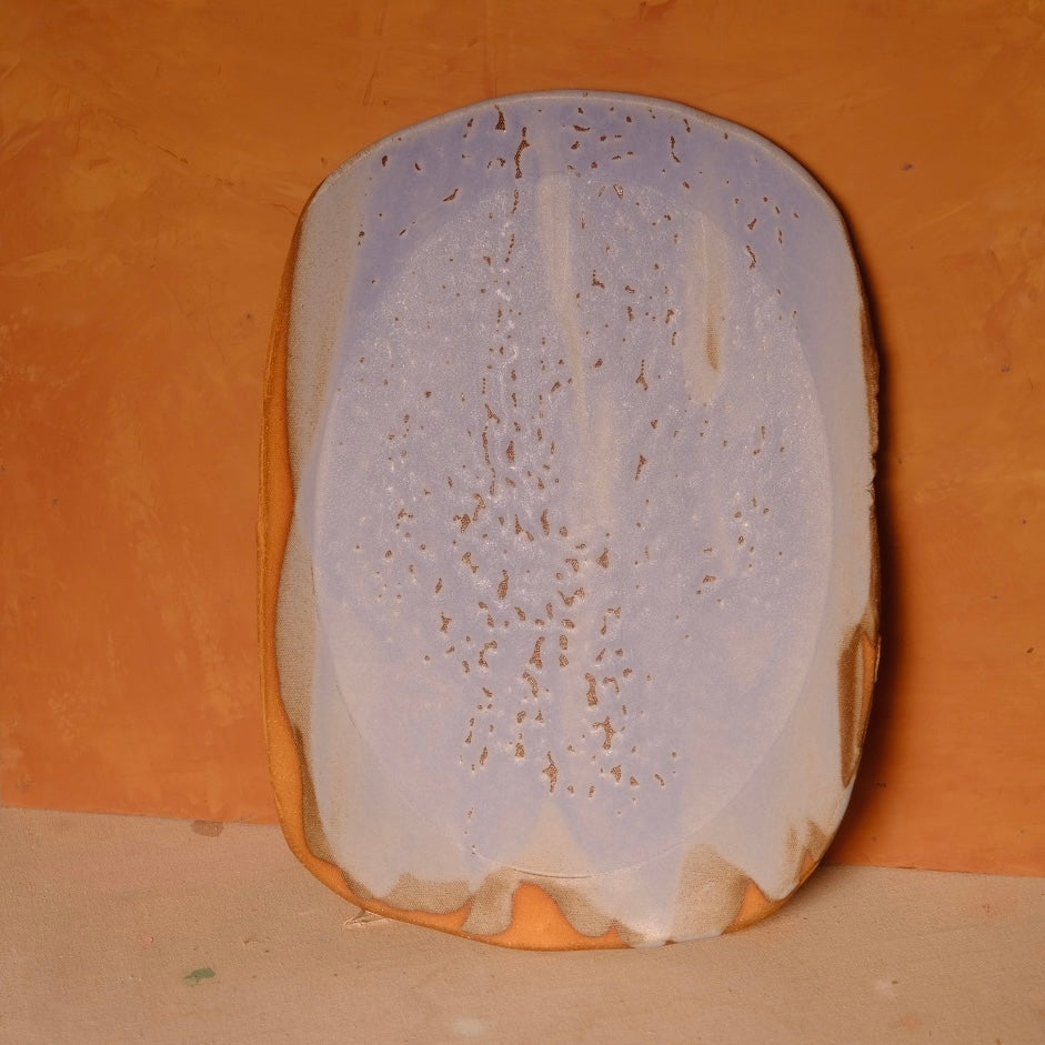 Wide Tera Platter with mottled lavender and cream glaze, propped upright showing irregular rim and raw clay edge.