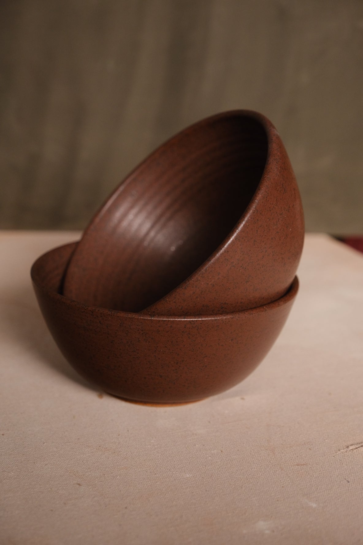 Speckled Buff Ramen Bowl, full side view of two bowls stacked askew on a neutral cloth tabletop