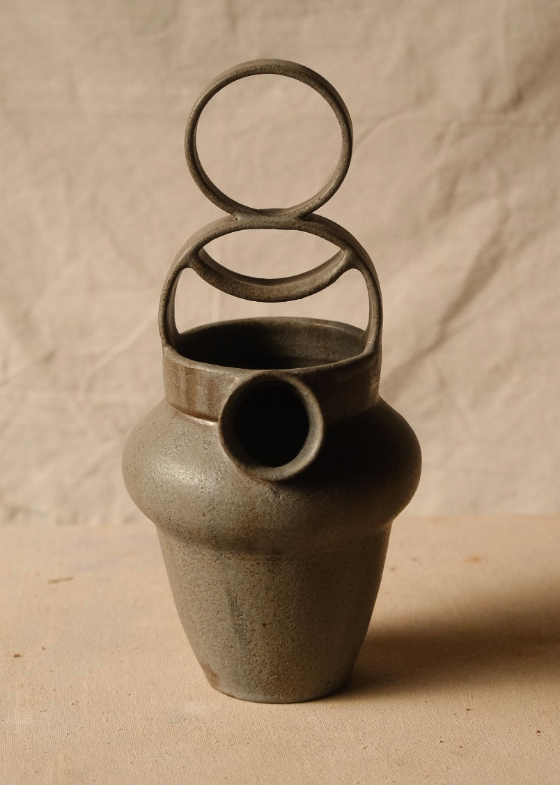 Rising Moon stoneware pitcher shown straight-on, featuring an empty tiered loop handle above the circular front spout.