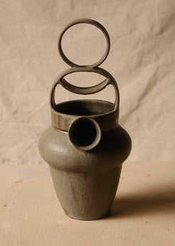 Rising Moon stoneware pitcher shown straight-on, featuring an empty tiered loop handle above the circular front spout.