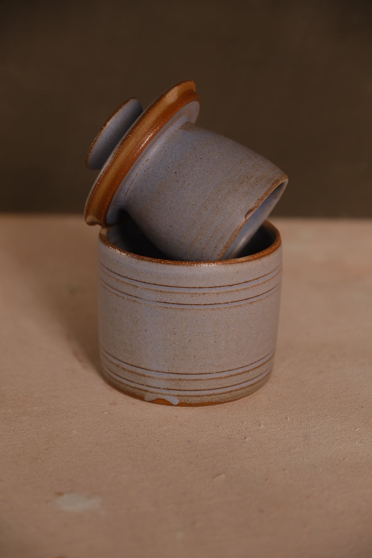 Butterbell keeper with carved grooves, bell lid angled on base, in a speckled pale blue glaze showing bare clay rim trims.