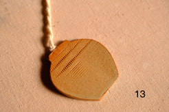 Ceramic ornament rounded jar cutout featuring stamped dash bands and fine horizontal line patterns, numbered thirteen.