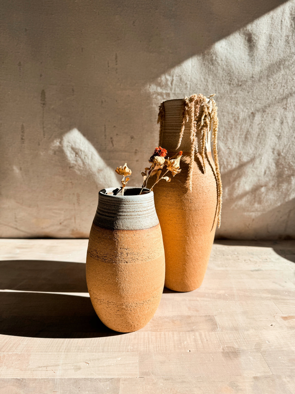 High Desert Vases duo angled forward, short barrel vase with dried flowers in front of taller textured vase