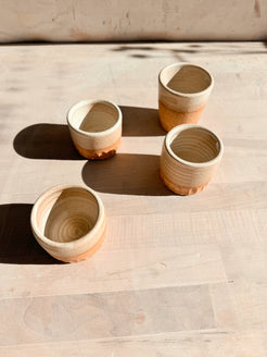 Aura Sipper ceramic cups, high-angle view looking down into four arranged stoneware cups on a pale wood table.