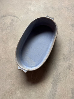 Speckle Cenote Hot Dish, oval ceramic casserole baker with side tab handles seen from above on a concrete surface.