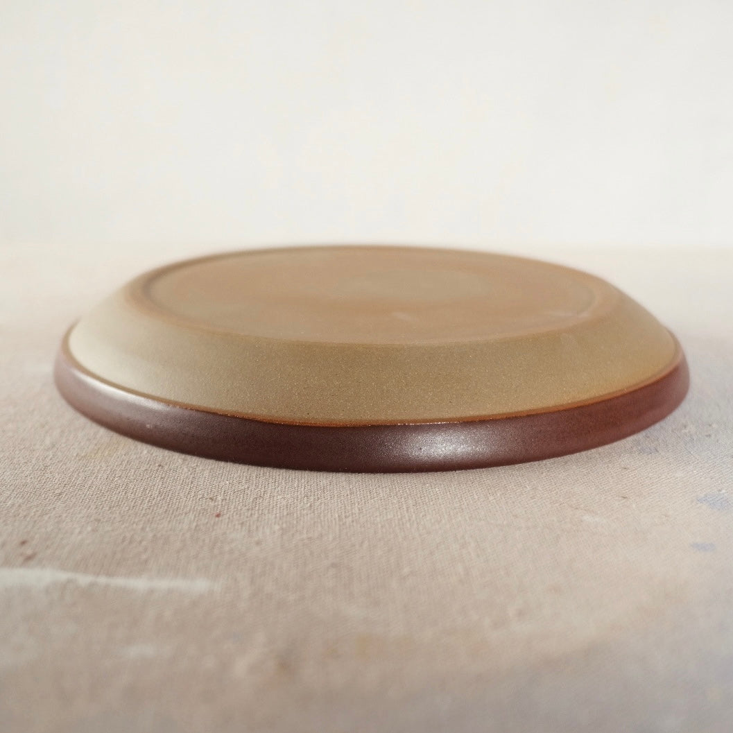 Country Rim Dinner Plate turned upside down on canvas, displaying the unglazed raw stoneware underside and glazed rim.