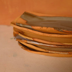 Narrow Tera Platter stacked in a set of four ceramic dishes, showing side profiles of raw terracotta rims.