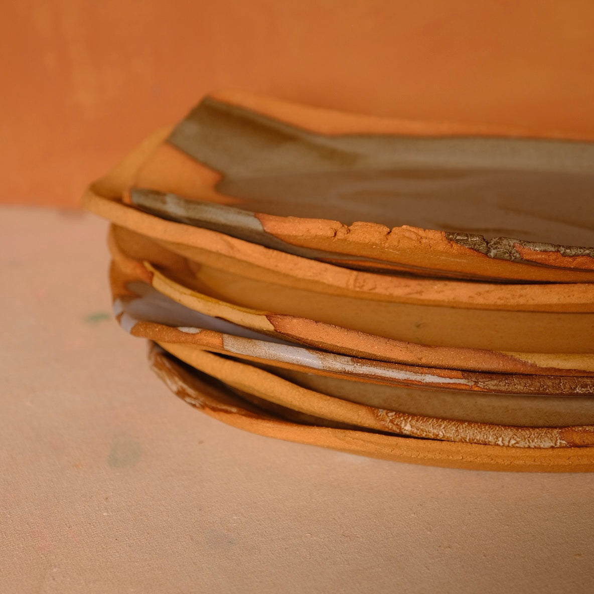 Narrow Tera Platter stacked in a set of four ceramic dishes, showing side profiles of raw terracotta rims.