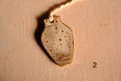 Ceramic ornament tapered vase shape with speckled oatmeal glaze and carved bands near the bottom, numbered two.