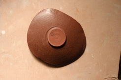Mesa Platter flipped over, flat overhead angle revealing the circular unglazed center foot and dark glazed back.