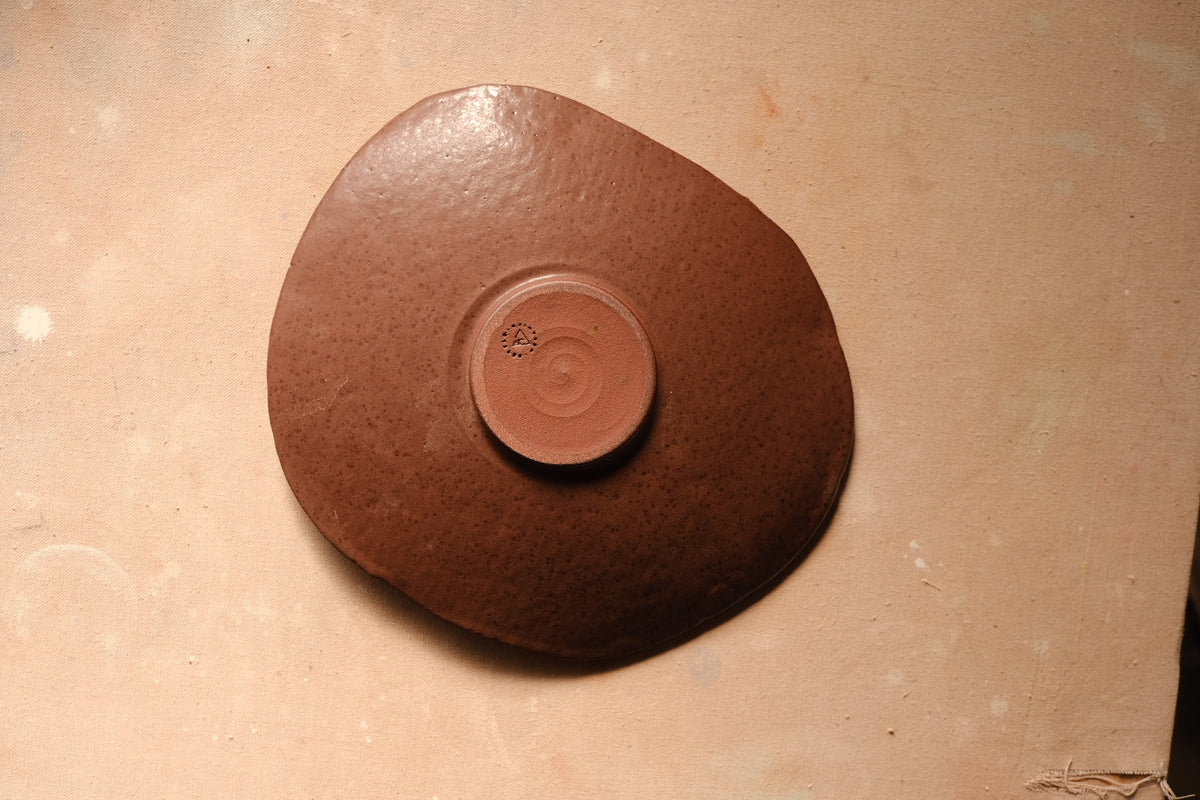 Mesa Platter flipped over, flat overhead angle revealing the circular unglazed center foot and dark glazed back.
