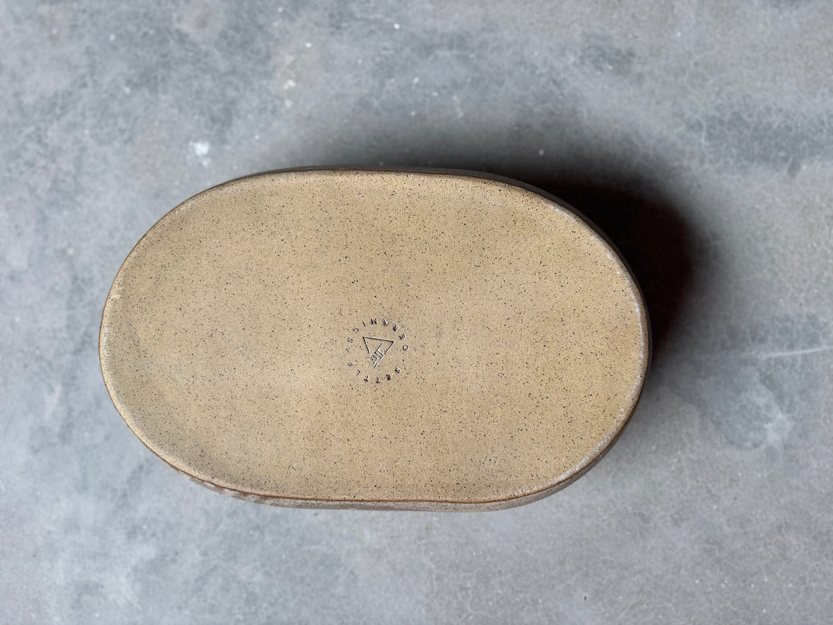 Speckle Maize Hot Dish, flat raw clay bottom stamped with the Settle Ceramics maker mark on concrete.