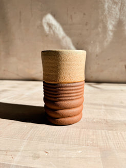 Textured Tumbler: straight ceramic cup with a warm tan glazed top and deeply ridged raw clay base on pale wood.