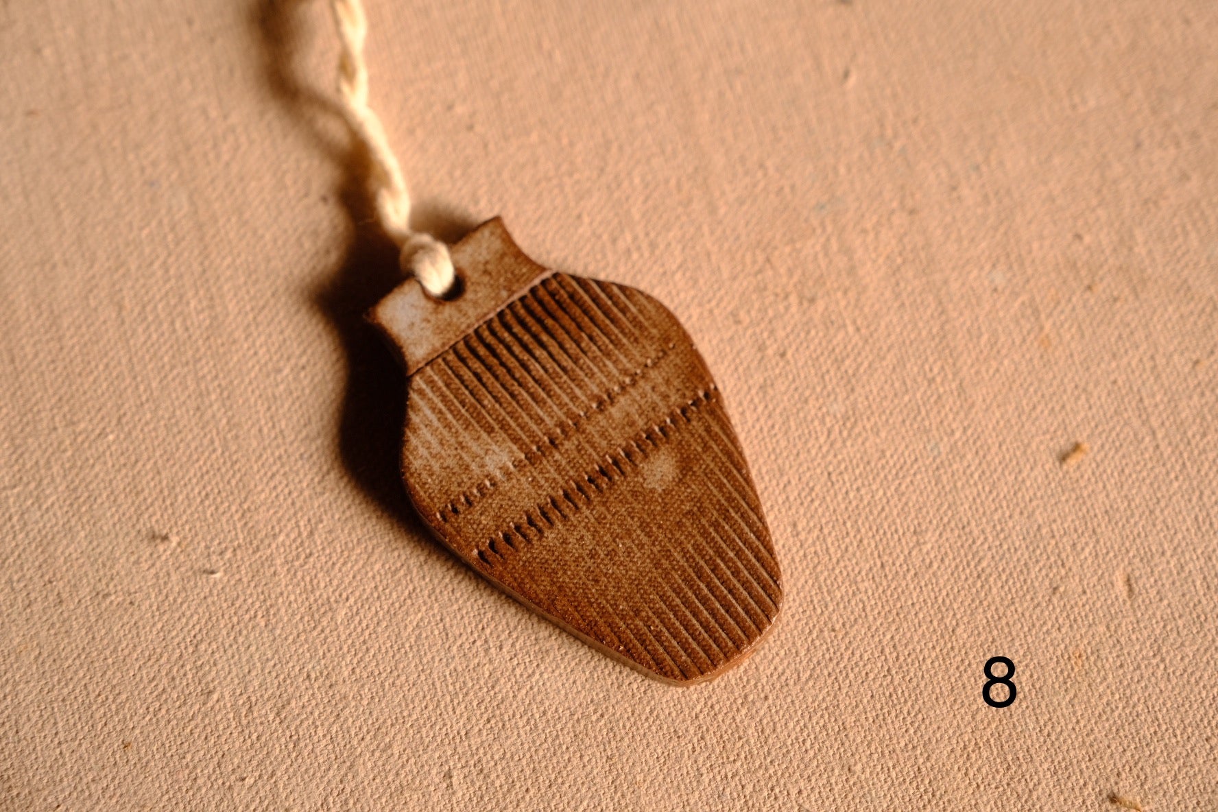 Ceramic ornament bulbous vase silhouette covered in vertical ribbed texture and a dashed cross band, numbered eight.