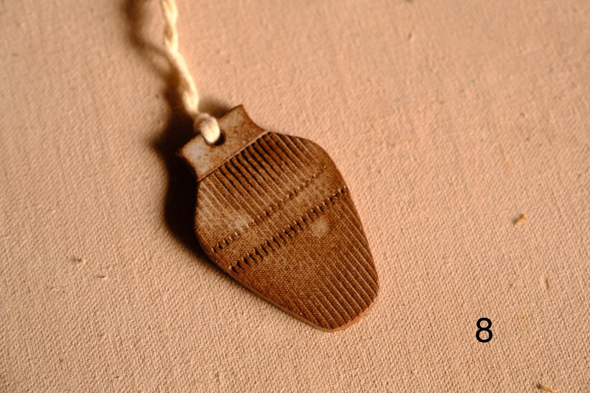 Ceramic ornament bulbous vase silhouette covered in vertical ribbed texture and a dashed cross band, numbered eight.