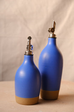 Wander Oil Bottle pair in cobalt blue glaze, small bottle in foreground with exposed clay foot on canvas.