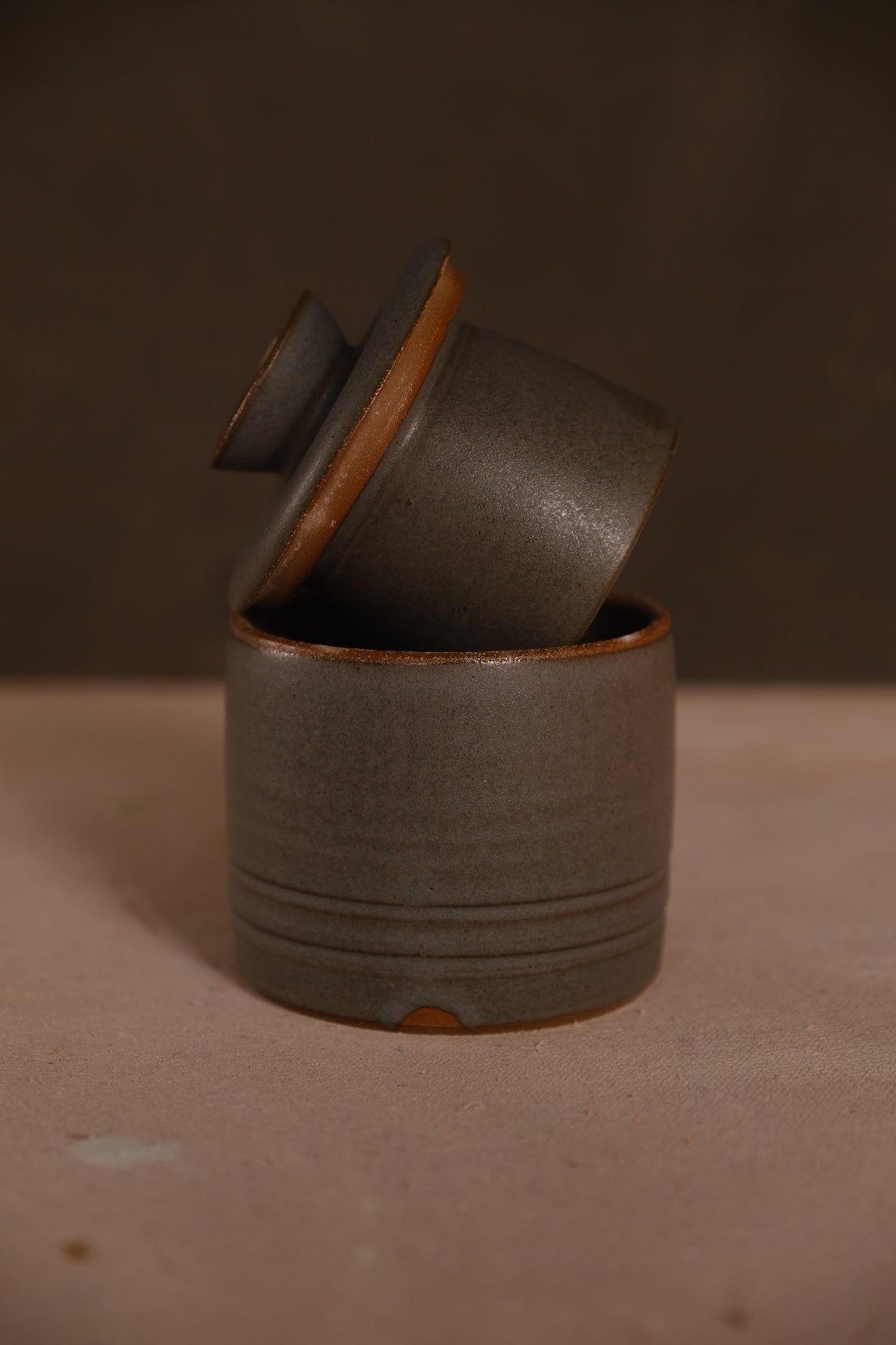 Butterbell crock with horizontal carved bands around base, tipped lid, finished in a matte charcoal glaze with raw clay rim.