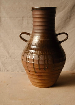 Woodfire Amphora #1, front view showing two loop handles, ribbed body texture, and glossy ash glaze dripping down the belly.