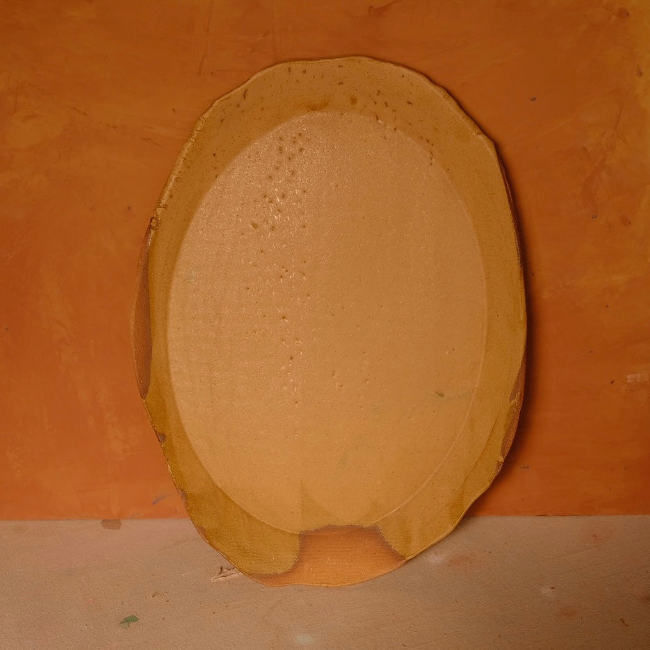 Wide Tera Platter with glossy ochre glaze and fine specks, standing upright displaying an oval basin and flared rim.