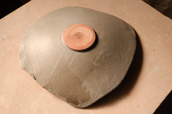 Mesa Platter turned upside down, showing unglazed circular foot with impressed studio stamp and glaze drip marks.