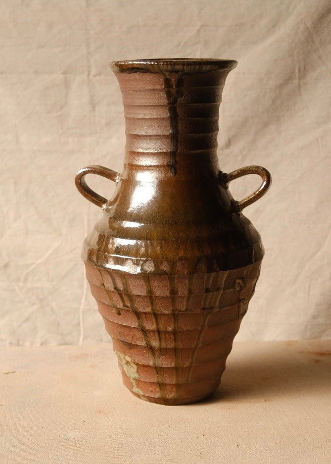 Woodfire Amphora #2, front view showing two loop handles and vertical glaze drips over a ribbed clay lower body.