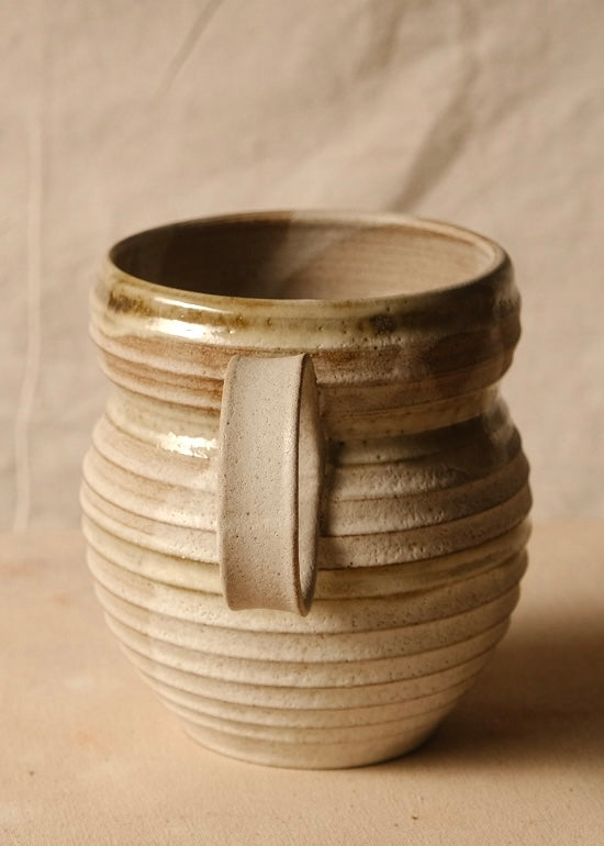 OO Amphora turned to face one strap handle forward, displaying deep horizontal wheel ridges and a glossy rim.