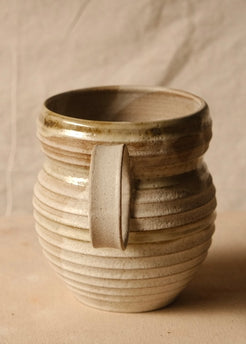 OO Amphora turned to face one strap handle forward, displaying deep horizontal wheel ridges and a glossy rim.
