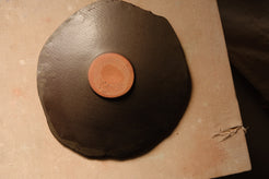 Mesa Platter base viewed from above, displaying the terracotta-toned round foot against a dark satin underside.