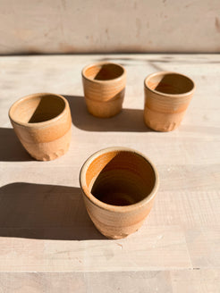 Aura Sipper cups, high-angle view focused on an open stoneware cup in the foreground with three cups spaced behind.