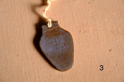 Ceramic ornament vase silhouette featuring a mottled blue and brown speckled glaze with hanging string, numbered three.