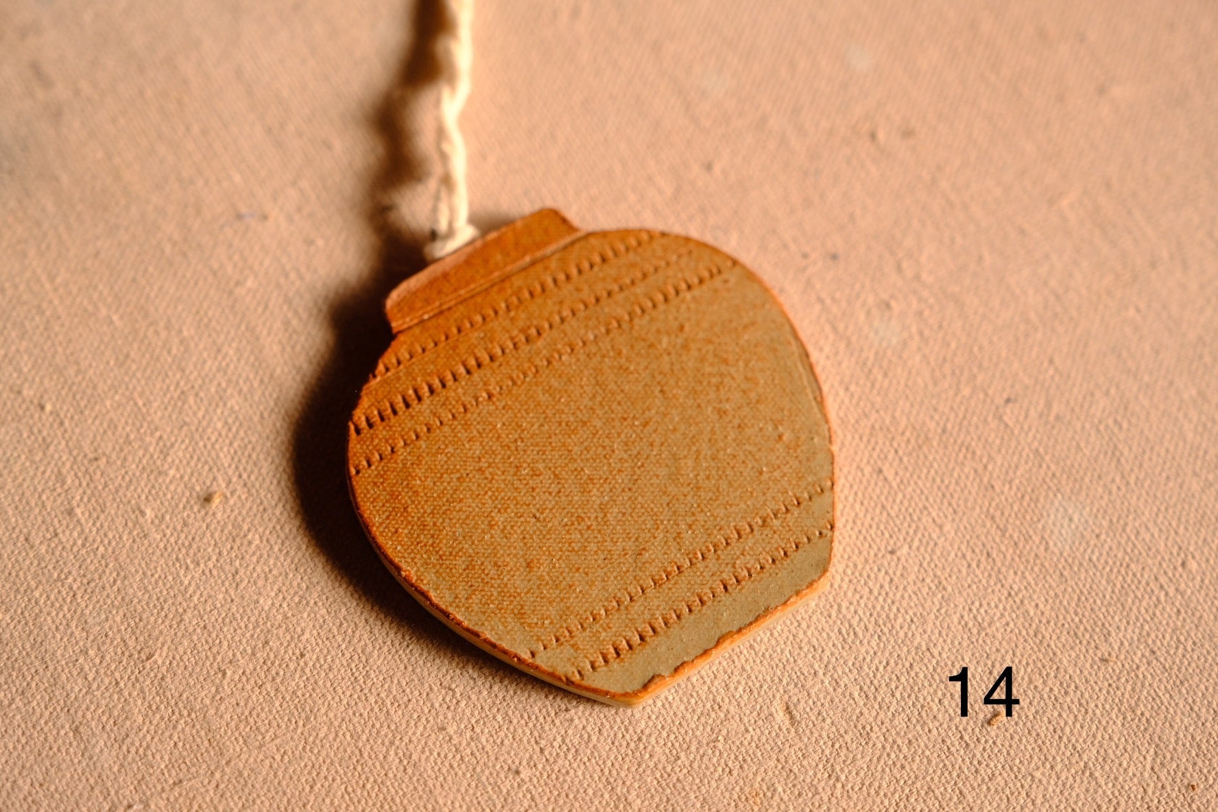 Ceramic ornament round jar shape with three horizontal rows of stamped dashed indentations, numbered fourteen on fabric.