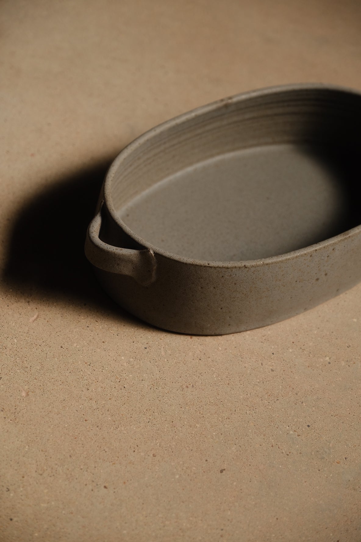 Storm Hot Dish: close-up view cropped near one side loop handle, showing interior throwing rings on a flat surface.