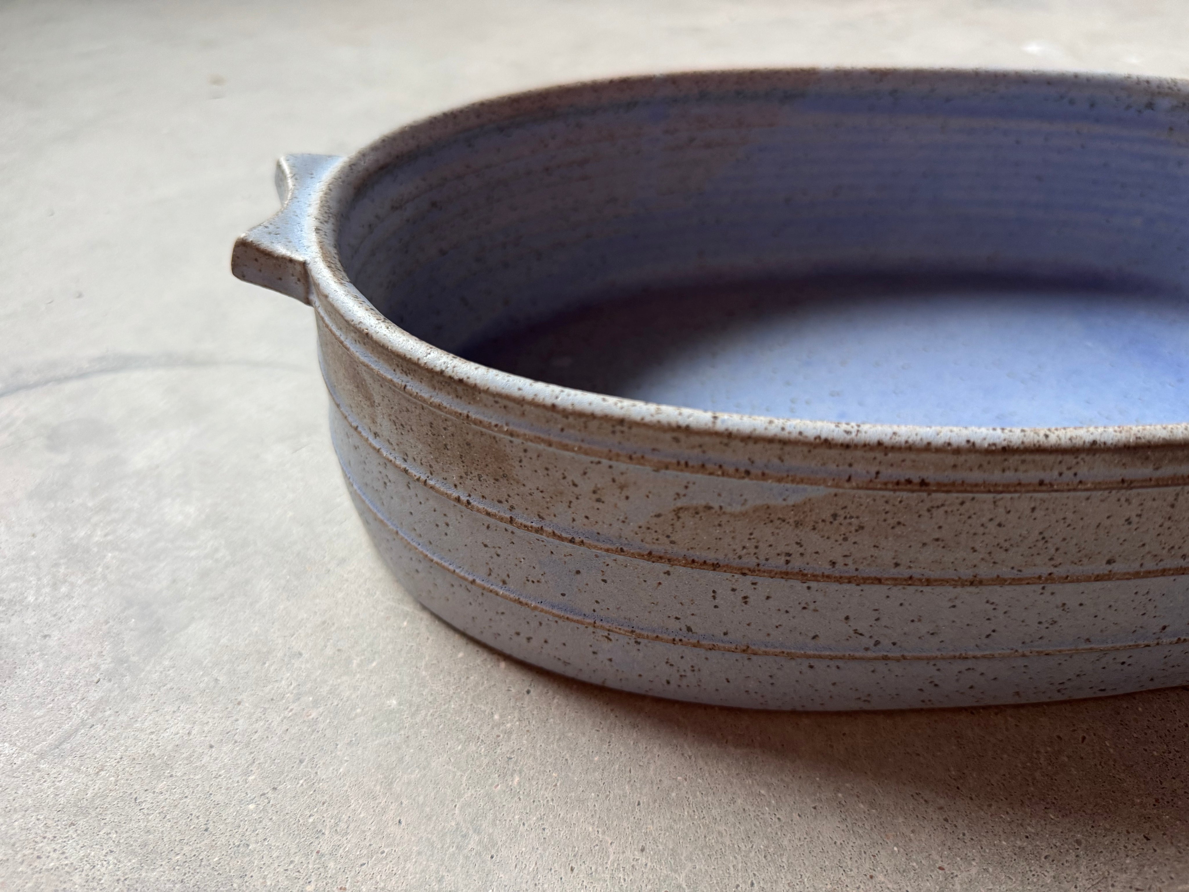 Speckle Cenote Hot Dish, eye-level side profile showing horizontal carved grooves, tab handle, and speckled exterior.
