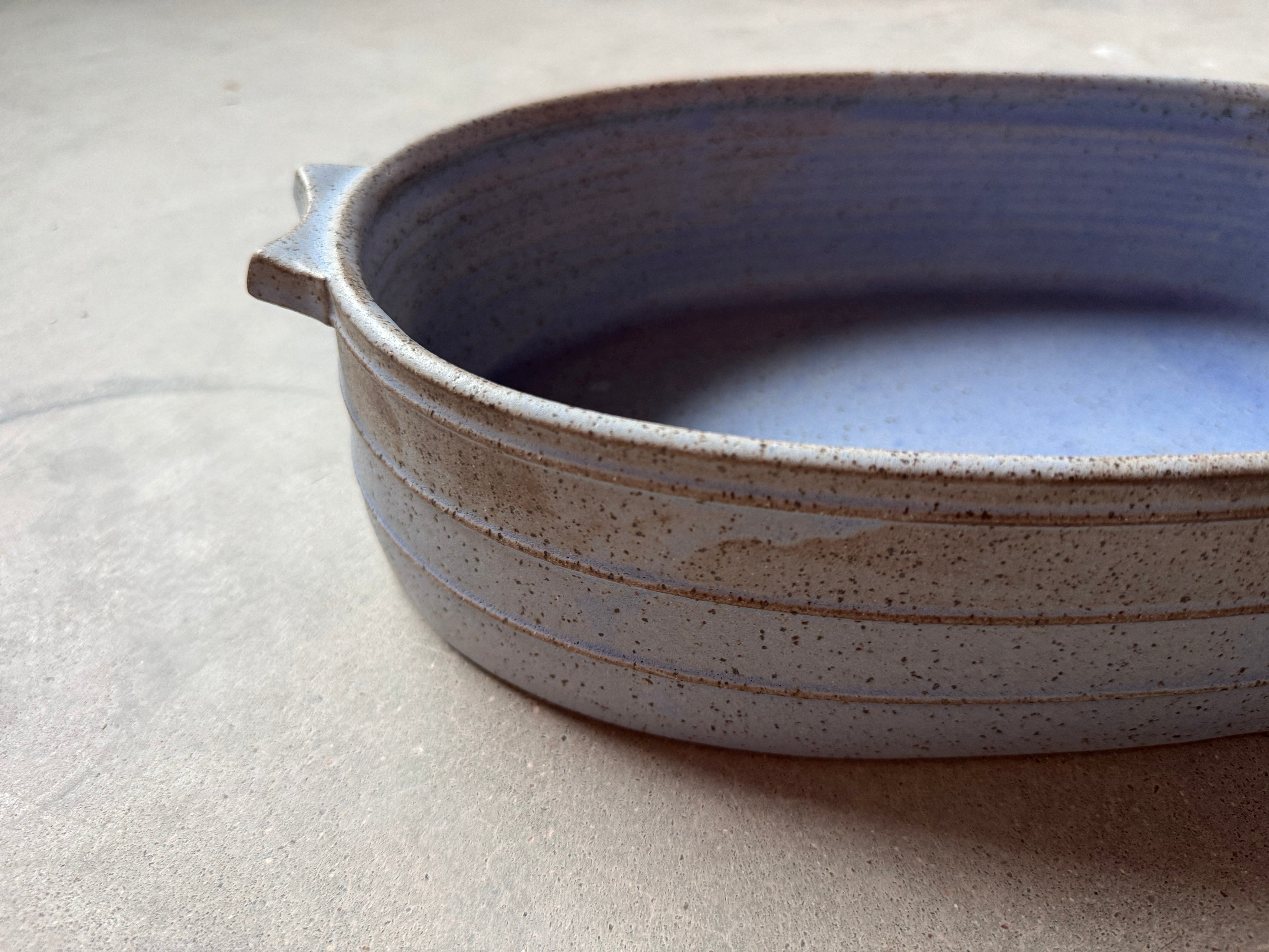 Speckle Cenote Hot Dish, eye-level side profile showing horizontal carved grooves, tab handle, and speckled exterior.