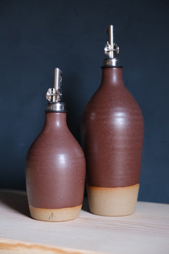 Wander Oil Bottle pair in deep umber satin glaze, small bottle in front showing a stamped clay foot.