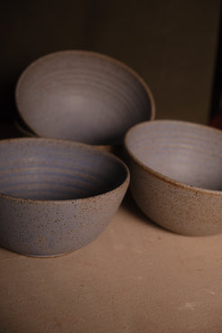 Speckled Buff Ramen Bowl, group of three stoneware bowls resting on a canvas surface in warm studio light
