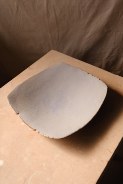 Mesa Platter with matte pale glaze, angled side view resting on a studio board with a slight rim curve.