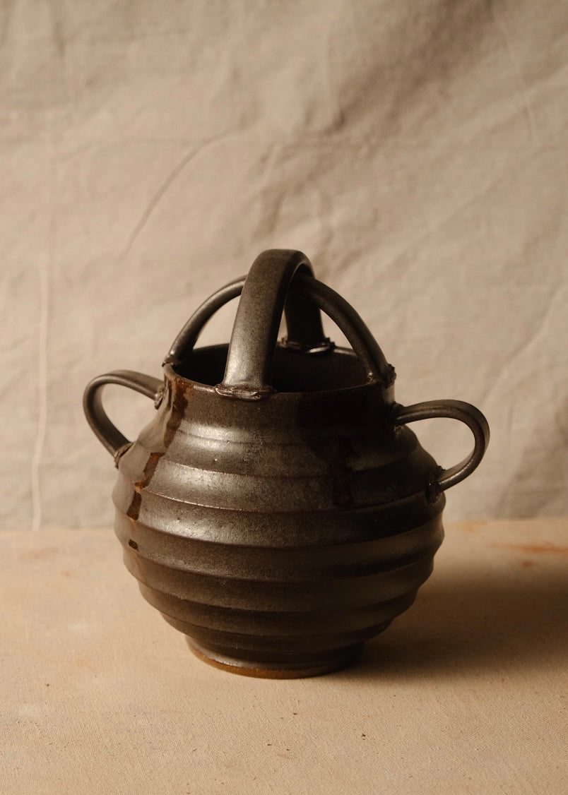 Regal glazed stoneware vase with horizontal ridges, arched top handles, two side loops, and an unglazed foot.