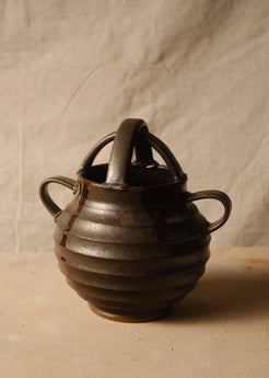 Regal glazed stoneware vase with horizontal ridges, arched top handles, two side loops, and an unglazed foot.