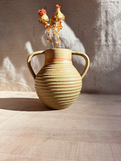 Iona Amphore speckled glazed ceramic vase with ribbed body and two looped handles, holding dried flowers on a wood surface.