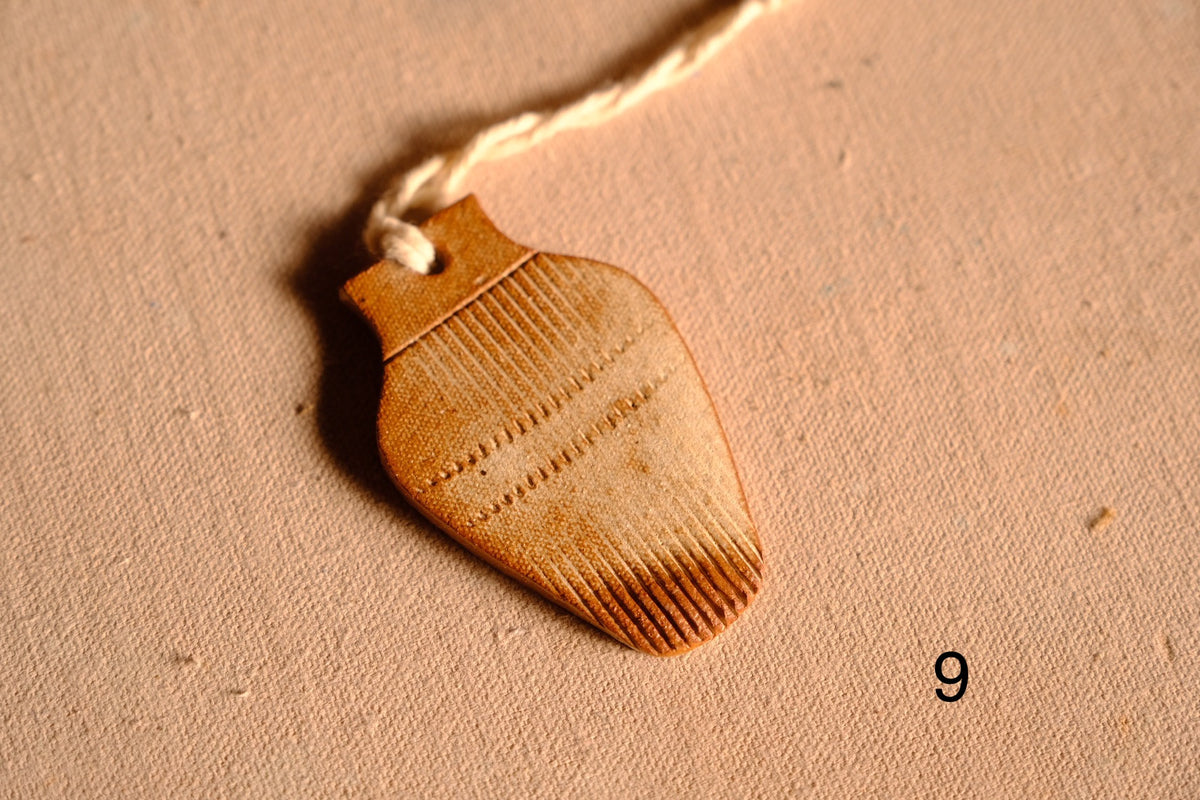 Ceramic ornament vase silhouette with comb-textured line patterns on the top and bottom sections, numbered nine.