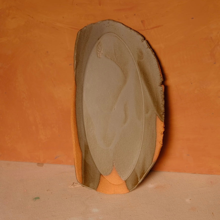 Narrow Tera Platter shown upright with broad asymmetrical glaze dip and exposed terracotta rim edges.