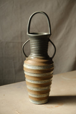 Eros Amphora ceramic vase with arched overhead handle and two side handles, lit from the right on a neutral surface.