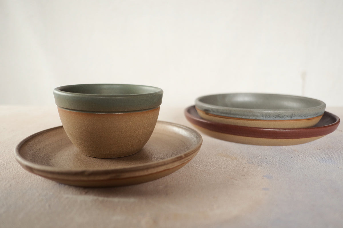 Country Rim Lunch Plate holding a matching small bowl, set in the foreground beside a stack of two stoneware plates.
