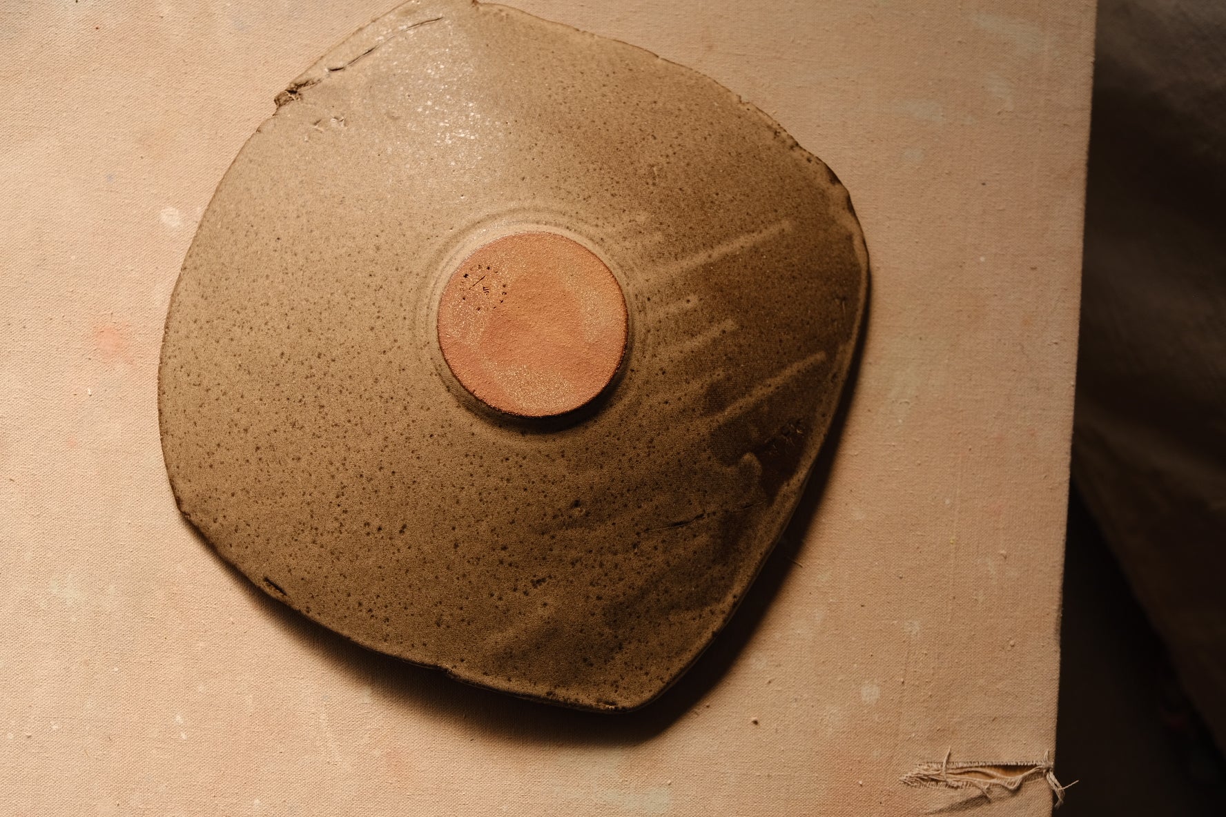 Mesa Platter inverted on canvas board, showing the circular stamped foot with pale glaze drips running outward.