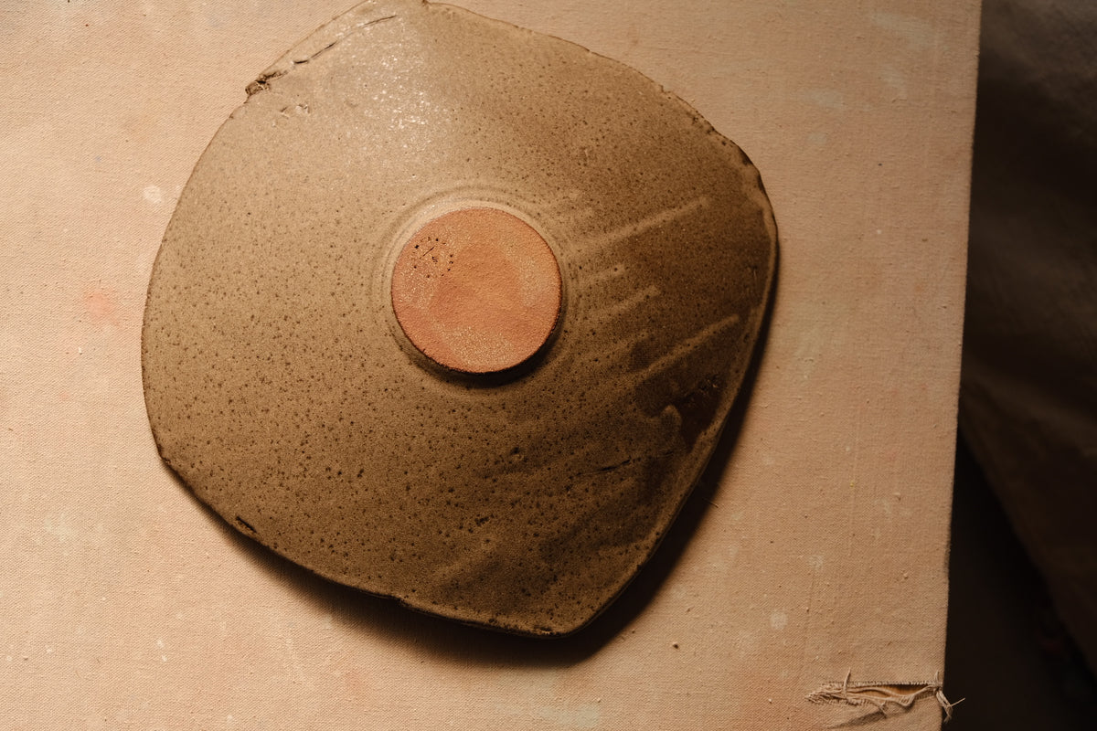 Mesa Platter inverted on canvas board, showing the circular stamped foot with pale glaze drips running outward.