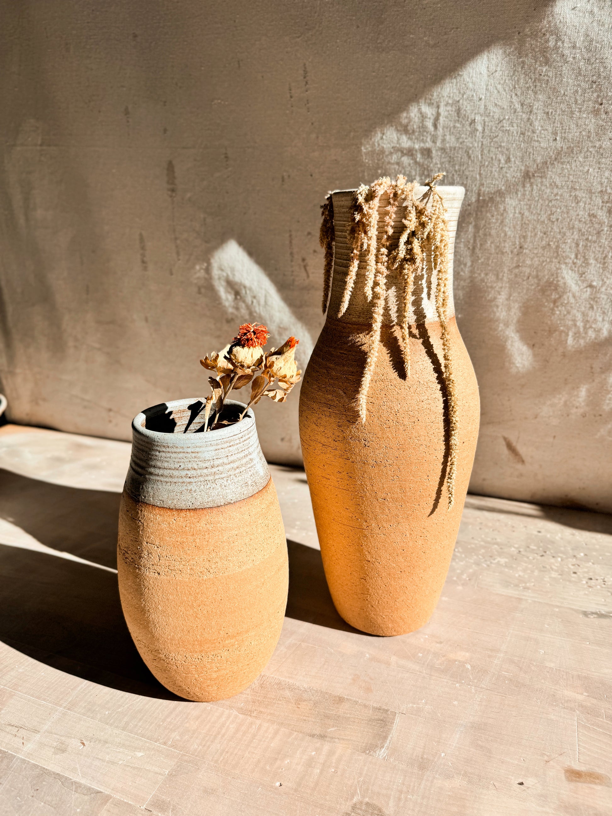 High Desert Vases pair on wooden table, short rounded vase with dried blooms beside taller vase holding dried amaranth