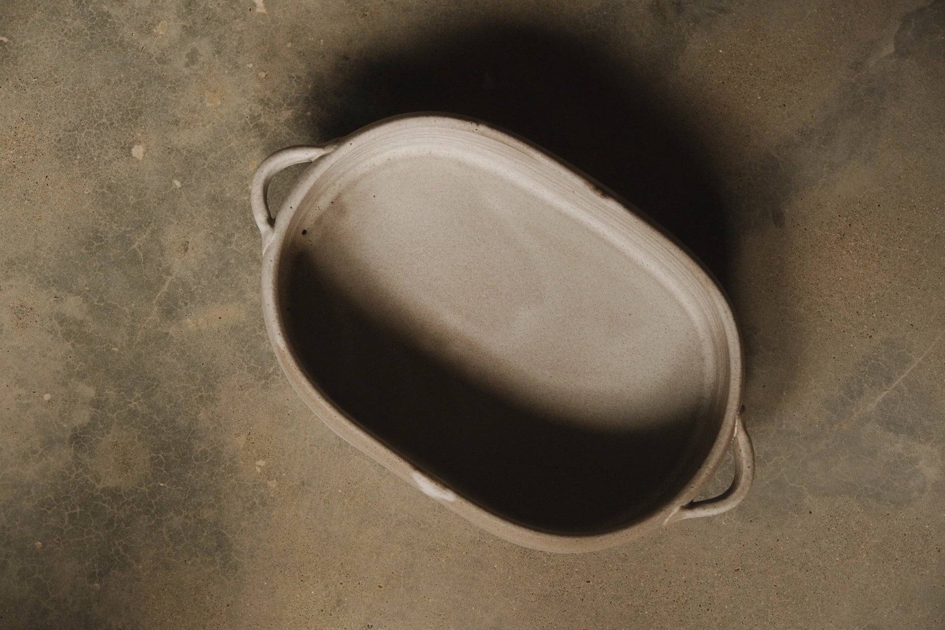 Blanca Hot Dish, full overhead bird's-eye view showing the interior, rim lines, and both looped handles on concrete.